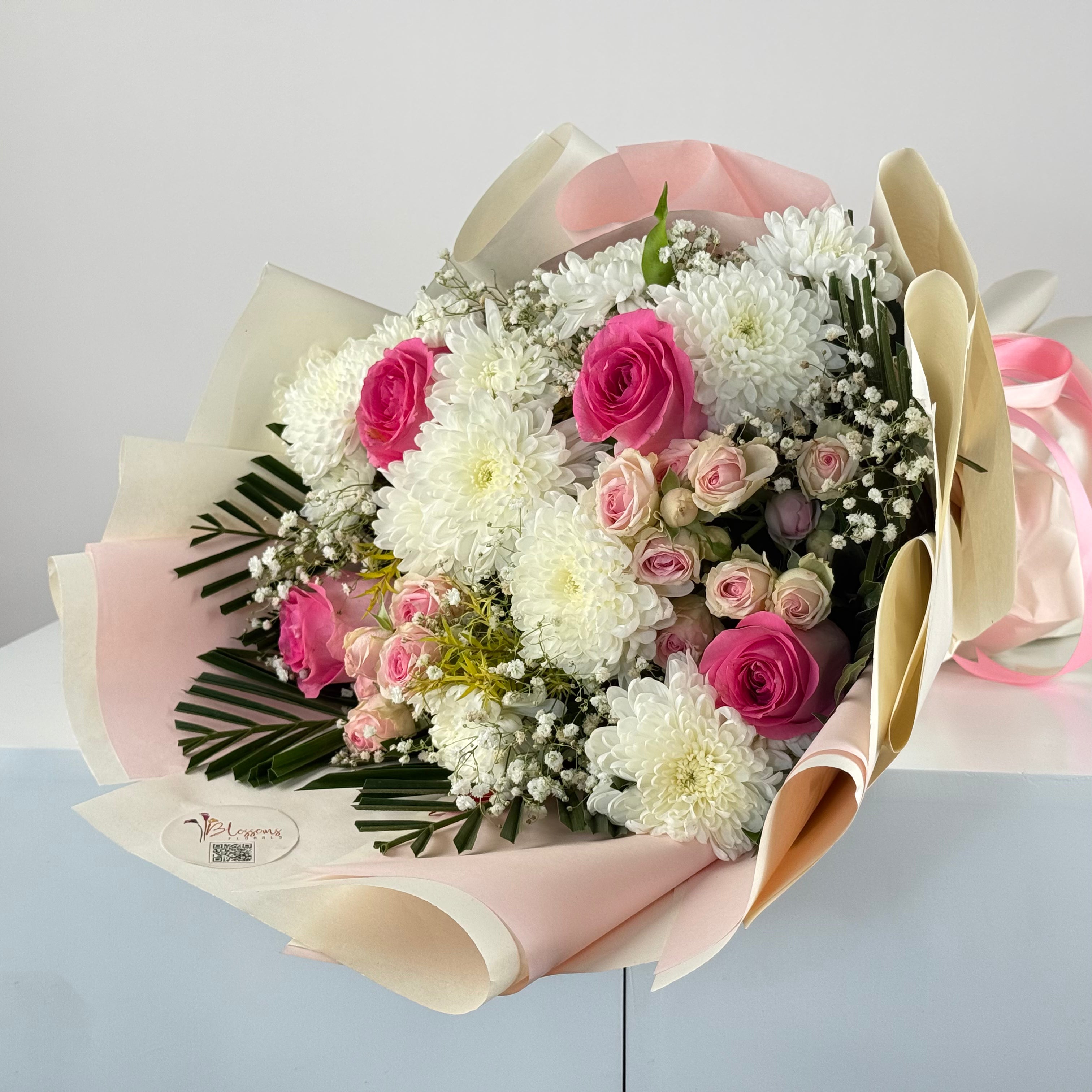 Bouquet of pink and white flowers with a visible brand label on a light gray background