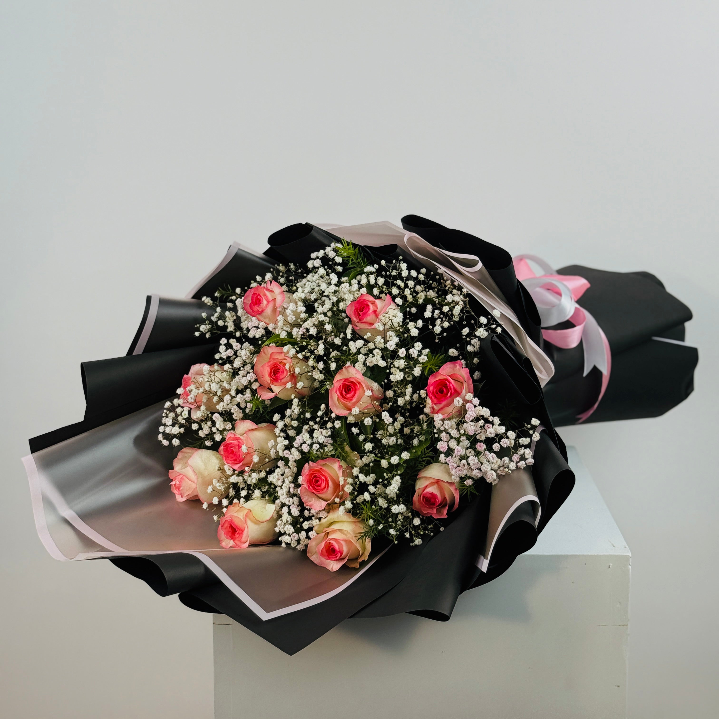 Bouquet of pink roses with black ribbon on a white background
