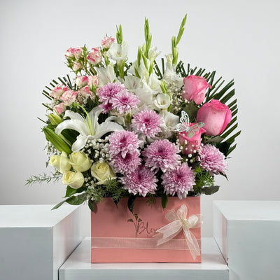 Floral arrangement in a pink box with a white background