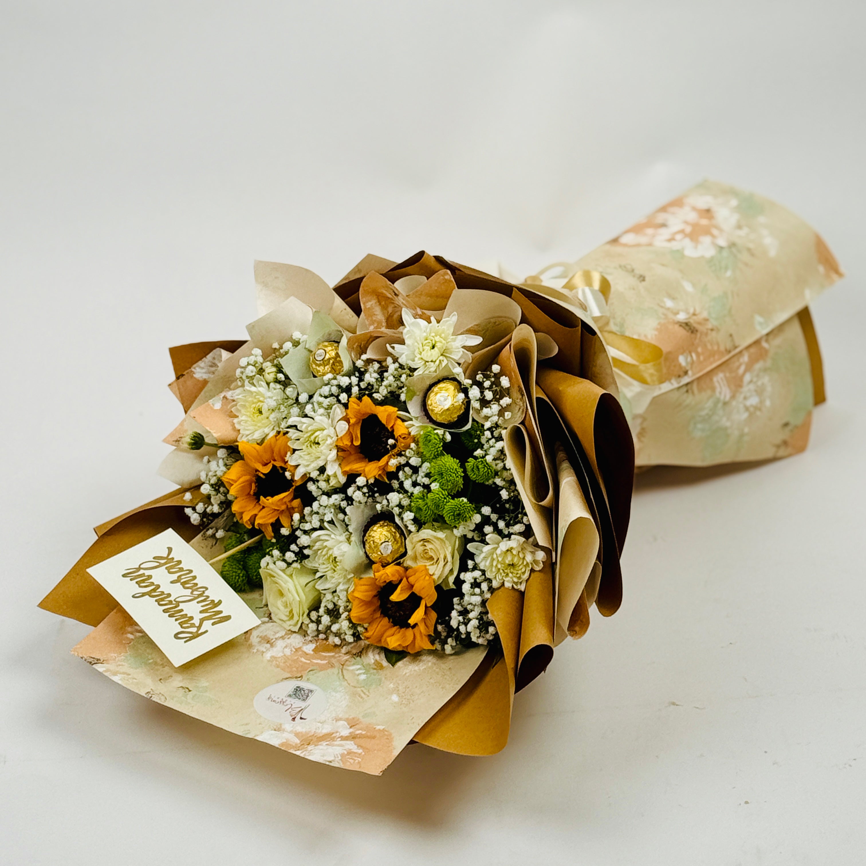 Bouquet of flowers wrapped in brown paper with a card on a white background