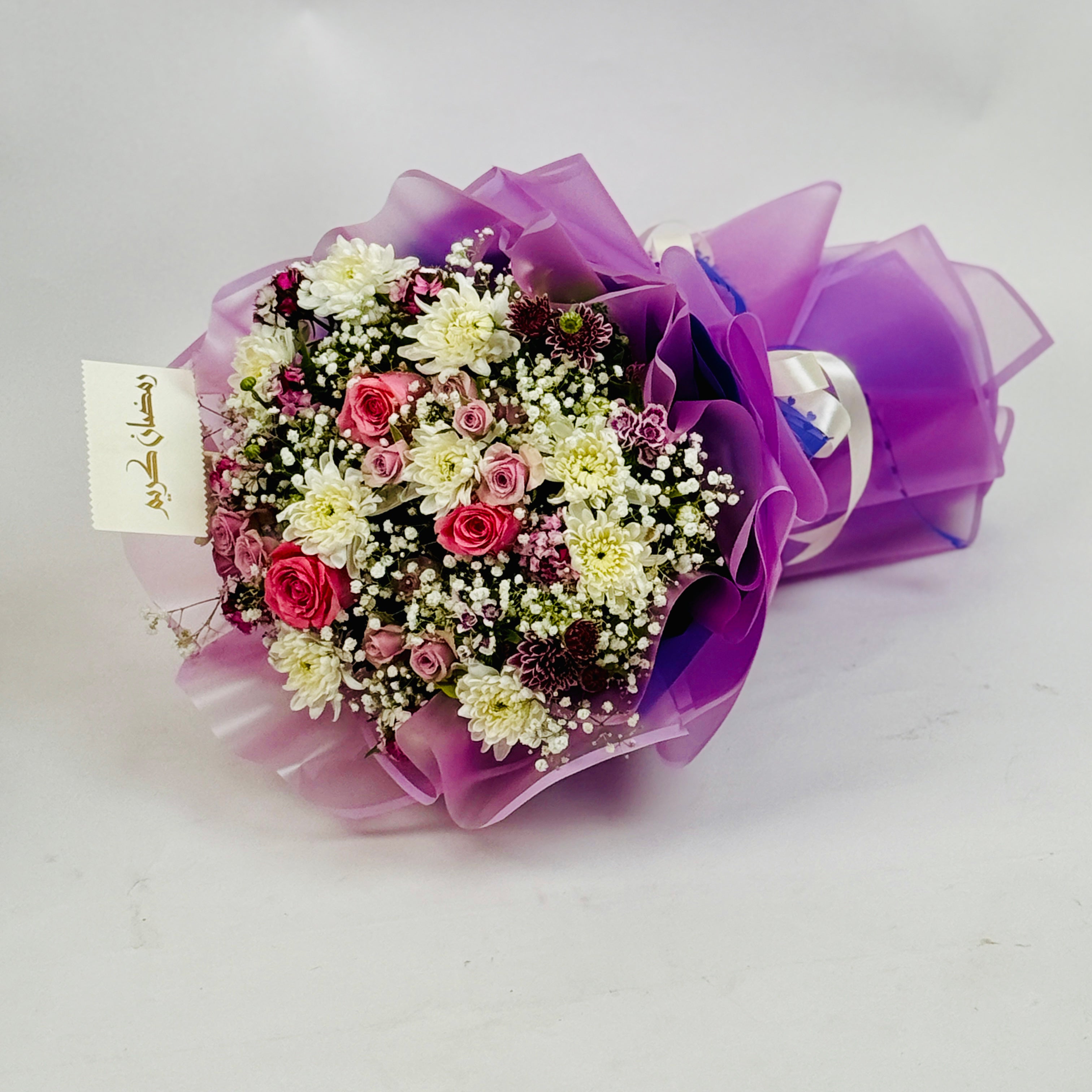 Bouquet of flowers wrapped in purple paper on a white background